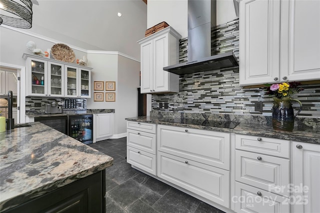 kitchen with wall chimney range hood, white cabinets, backsplash, and black electric cooktop