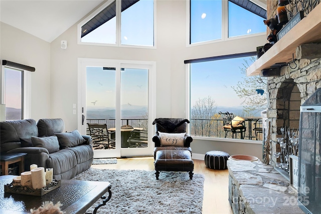 living room with high vaulted ceiling, a wealth of natural light, and wood finished floors