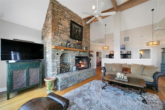 living area featuring visible vents, wood finished floors, a fireplace, ceiling fan, and high vaulted ceiling