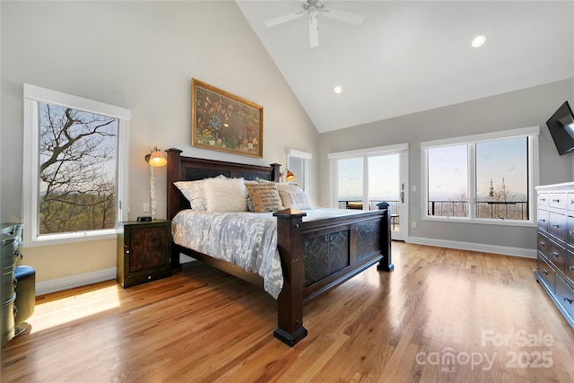 bedroom featuring light wood-style floors, high vaulted ceiling, multiple windows, and access to exterior