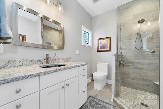 full bath featuring vanity, toilet, baseboards, and a stall shower