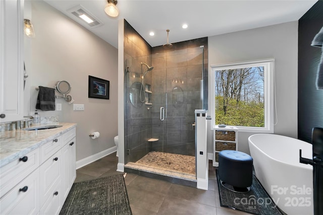 bathroom featuring a freestanding bath, a stall shower, vanity, baseboards, and toilet