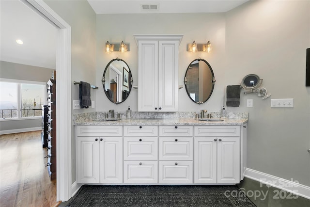 bathroom with visible vents, a sink, baseboards, and double vanity