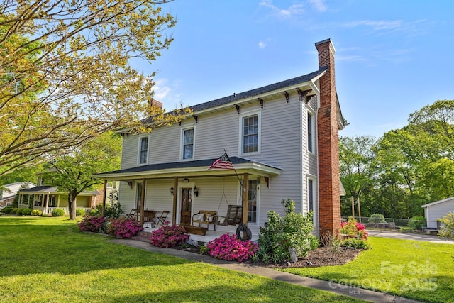 view of front of house with fence, a front yard, a porch, and a chimney
