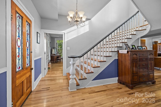 entrance foyer with baseboards, stairway, an inviting chandelier, and light wood-style floors