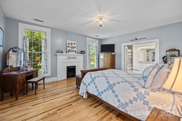 bedroom featuring a fireplace, visible vents, and wood finished floors