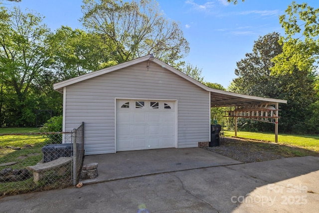 garage featuring driveway, fence, and a garage