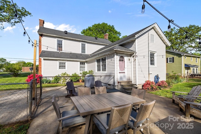 back of house featuring entry steps, a chimney, fence, a patio, and outdoor dining area