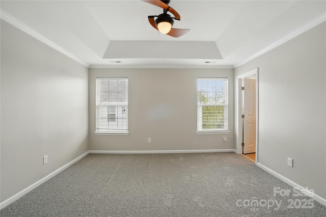 carpeted empty room with a tray ceiling, visible vents, baseboards, ceiling fan, and crown molding
