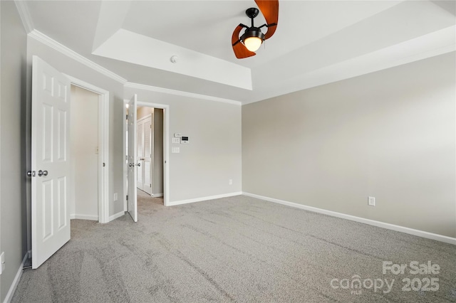 unfurnished bedroom with ceiling fan, carpet floors, a raised ceiling, baseboards, and ornamental molding