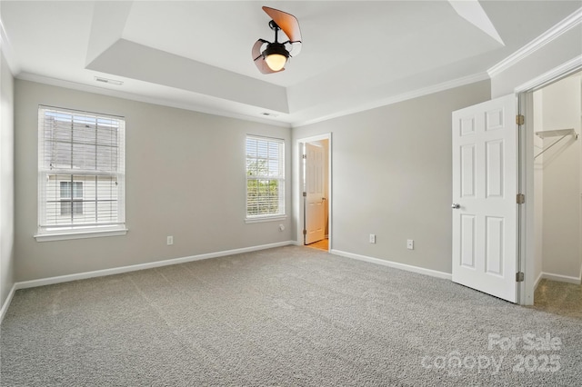 unfurnished bedroom with a tray ceiling, carpet floors, baseboards, and ornamental molding
