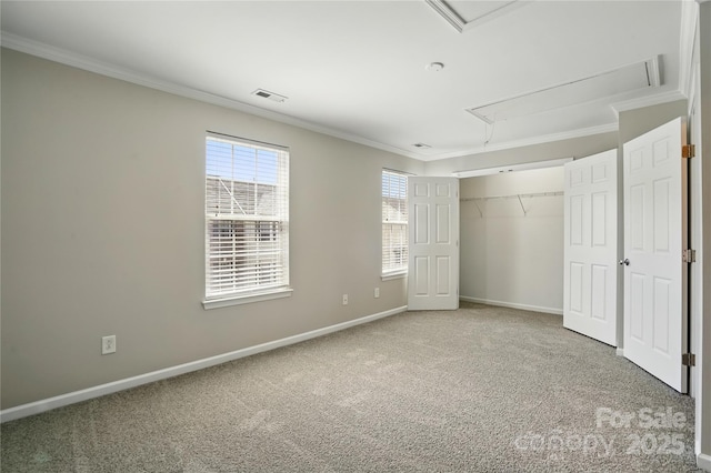 unfurnished bedroom with visible vents, ornamental molding, carpet floors, baseboards, and attic access