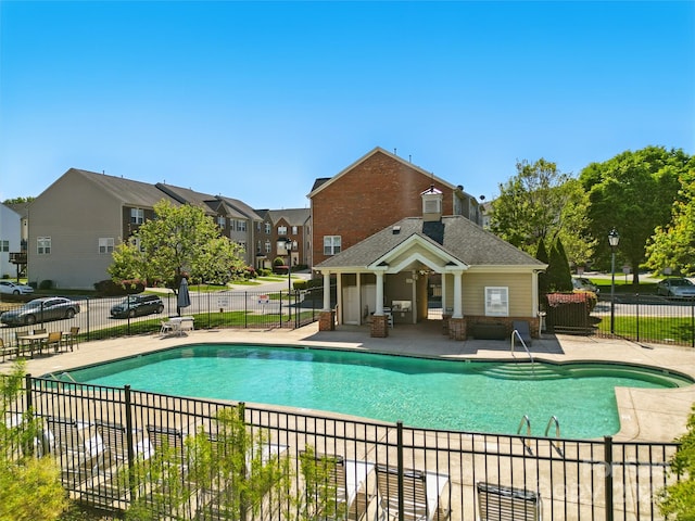 pool with a residential view, a patio area, and fence