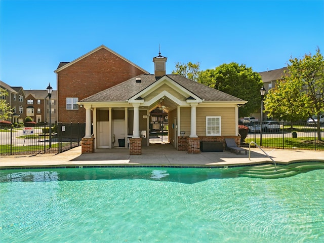 back of house featuring a patio area, a chimney, fence, a community pool, and brick siding