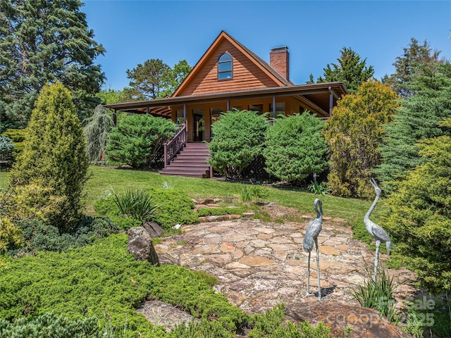 cabin featuring a chimney, a front lawn, a porch, and stairway