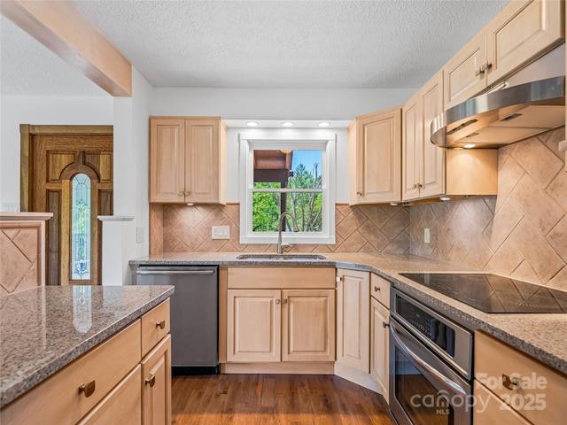 kitchen with light brown cabinetry, appliances with stainless steel finishes, a sink, a textured ceiling, and under cabinet range hood