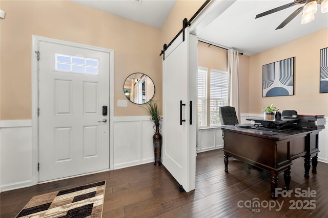 2262 Galloway Ln SW, Concord, NC 28025 - entrance foyer featuring a barn door, a wainscoted wall, a ceiling fan, dark wood-type flooring, and a decorative wall