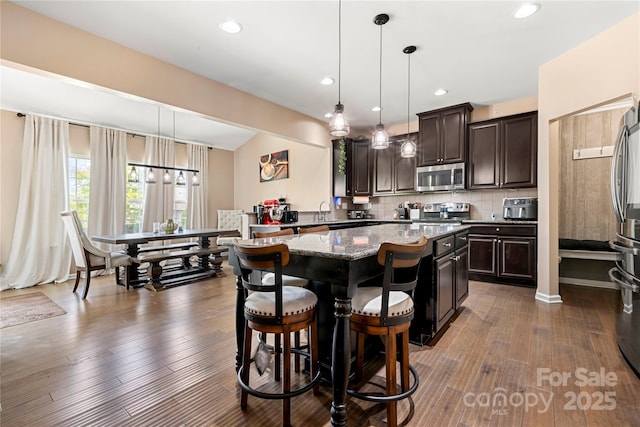 2262 Galloway Ln SW, Concord, NC 28025 - kitchen featuring dark brown cabinets, stainless steel appliances, light stone countertops, and a kitchen island