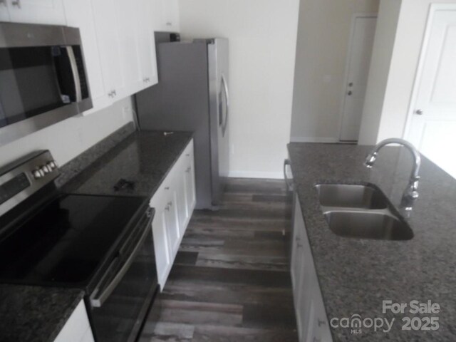 574 30th Avenue Cir NE, Hickory, NC 28601 - kitchen featuring dark stone countertops, a sink, dark wood-style flooring, white cabinetry, and stainless steel appliances