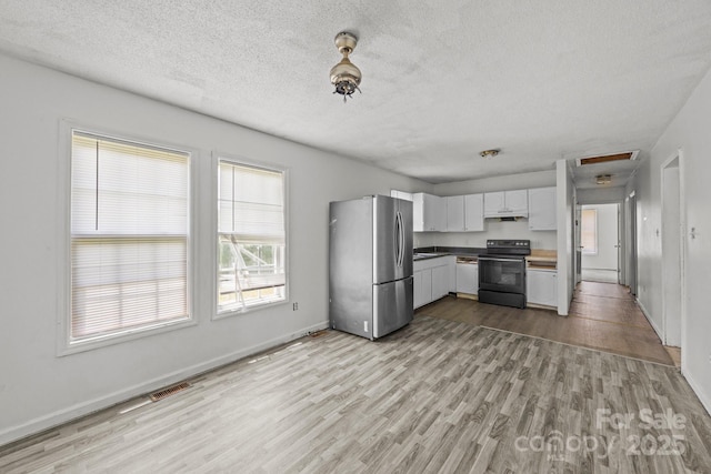 809 1st St E, Ahoskie, NC 27910 - kitchen with freestanding refrigerator, black / electric stove, light wood-style floors, a textured ceiling, and baseboards