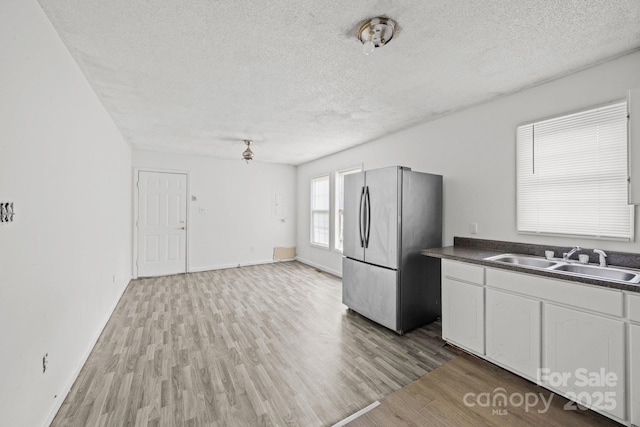 809 1st St E, Ahoskie, NC 27910 - kitchen with freestanding refrigerator, a sink, dark countertops, a textured ceiling, and wood finished floors