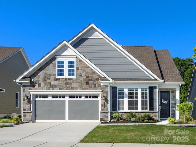 craftsman-style house with concrete driveway, a front yard, an attached garage, and stone siding