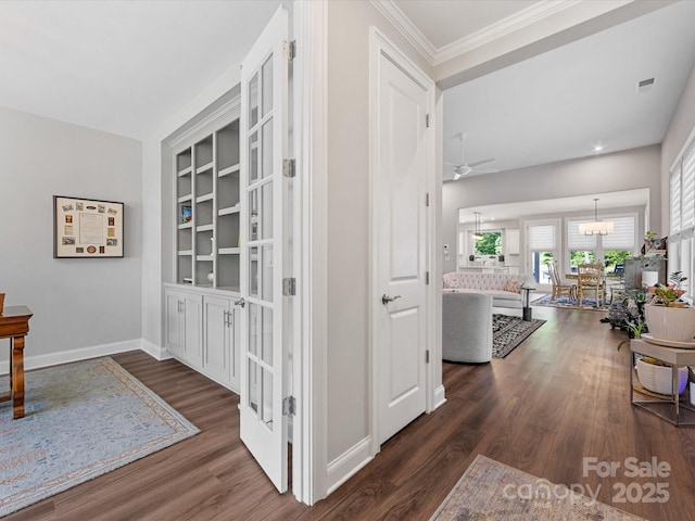 hallway featuring visible vents, crown molding, an inviting chandelier, wood finished floors, and baseboards