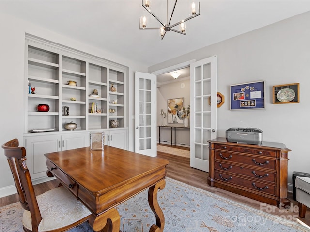home office featuring an inviting chandelier, french doors, and wood finished floors