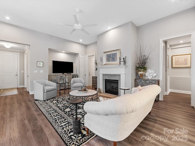 living room with baseboards, dark wood-style flooring, ceiling fan, and a fireplace