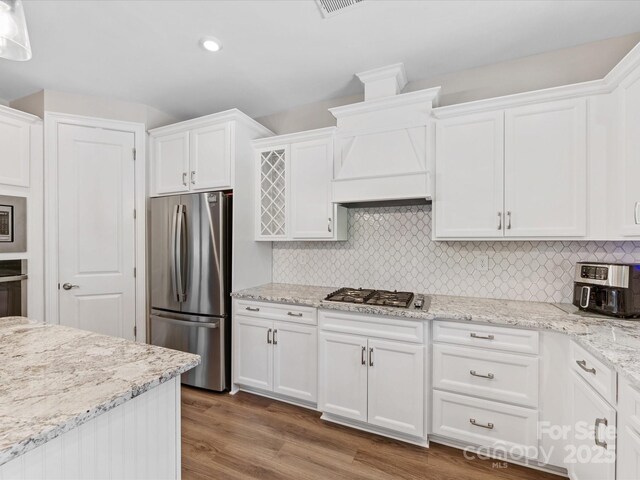 kitchen featuring white cabinets, stainless steel appliances, wood finished floors, and backsplash
