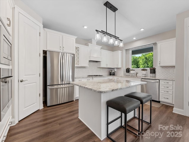 kitchen featuring appliances with stainless steel finishes, backsplash, dark wood finished floors, and white cabinetry
