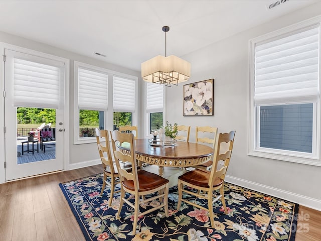 dining room with baseboards, visible vents, wood finished floors, and a notable chandelier