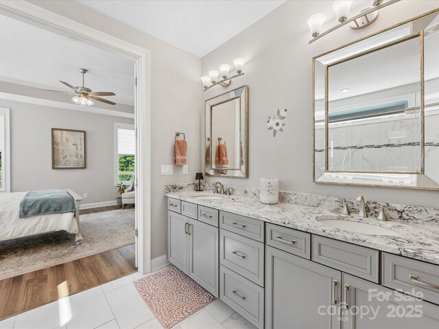 ensuite bathroom with double vanity, a sink, ceiling fan, and ensuite bath