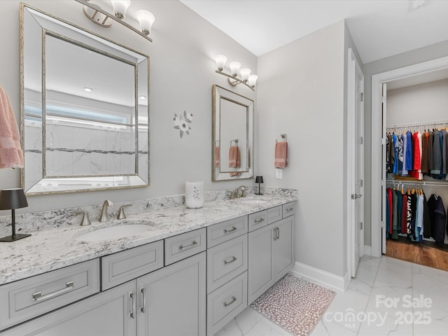 full bathroom featuring a sink, double vanity, marble finish floor, baseboards, and a spacious closet