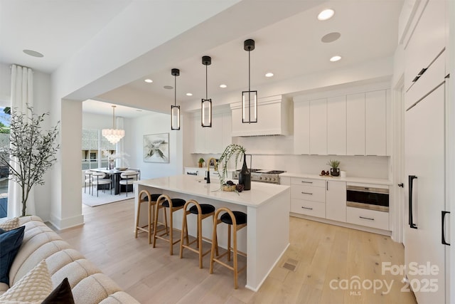 3473 Willow Oak Rd, Charlotte, NC 28209 - kitchen featuring recessed lighting, light countertops, light wood finished floors, and a kitchen bar