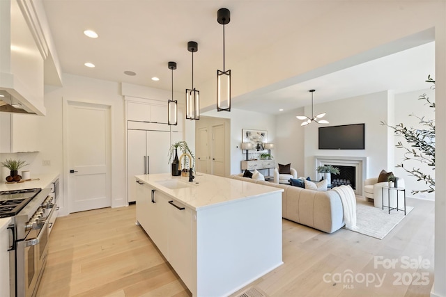 3473 Willow Oak Rd, Charlotte, NC 28209 - kitchen with wall chimney exhaust hood, white cabinetry, a sink, light wood finished floors, and double oven range
