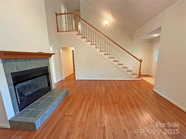 904 3rd Street Pl NE, Conover, NC 28613 - unfurnished living room with a tiled fireplace, ornamental molding, stairs, and wood finished floors