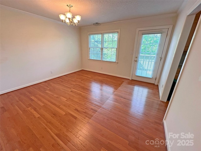 904 3rd Street Pl NE, Conover, NC 28613 - unfurnished room with crown molding, baseboards, light wood-style floors, and a chandelier