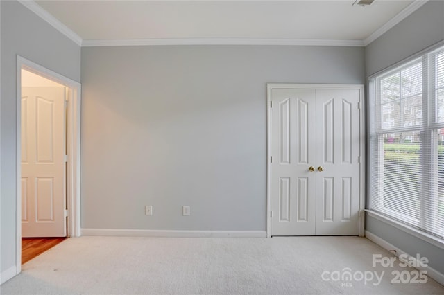 unfurnished bedroom with carpet flooring, visible vents, baseboards, a closet, and crown molding