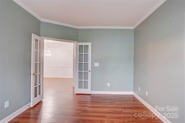 empty room featuring wood finished floors, baseboards, ornamental molding, and french doors