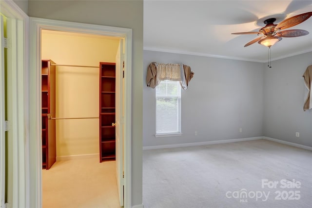 unfurnished bedroom with a closet, a walk in closet, carpet, baseboards, and ornamental molding