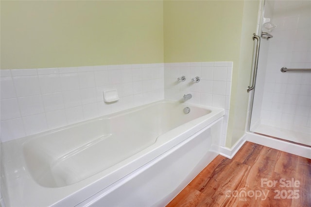 full bath featuring a bath, a shower stall, and wood finished floors