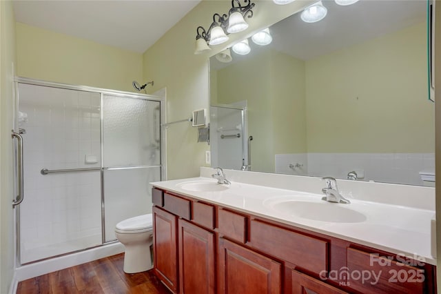 full bath with a shower stall, toilet, wood finished floors, and a sink