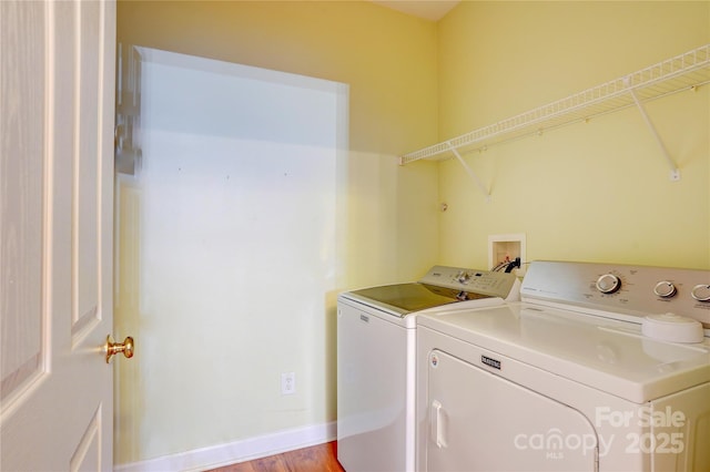 washroom with baseboards, separate washer and dryer, and laundry area