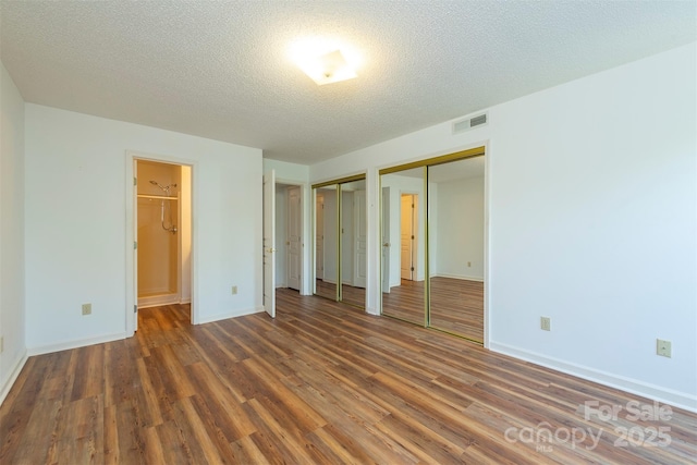 3101 Idle Hour Dr, Asheville, NC 28806 - unfurnished bedroom featuring multiple closets, wood finished floors, a textured ceiling, and connected bathroom