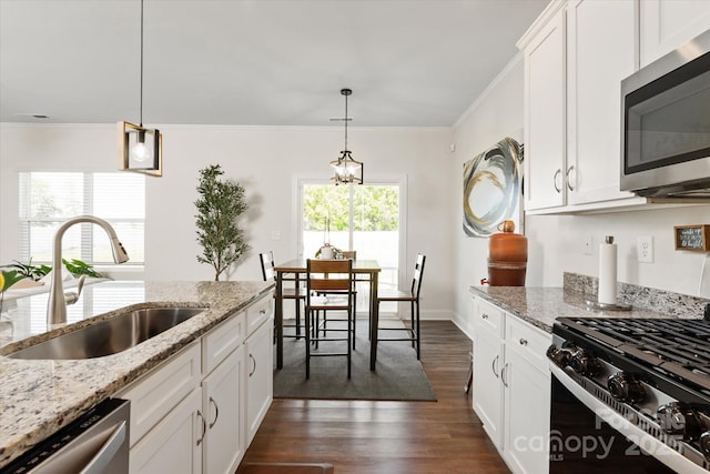 kitchen featuring an inviting chandelier, stainless steel appliances, white cabinets, a sink, and dark wood-style floors