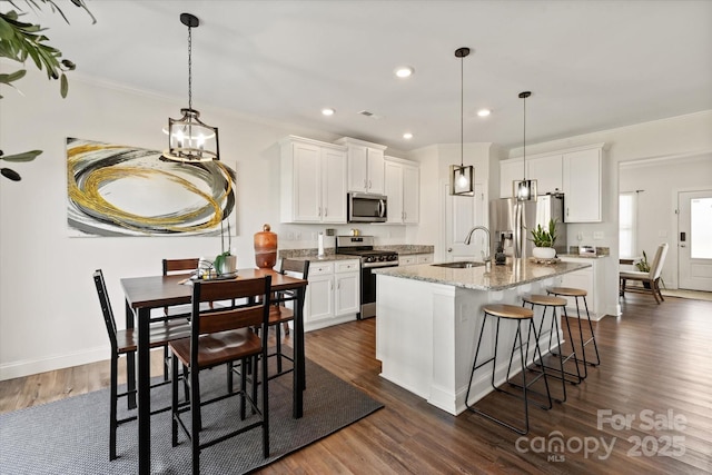 kitchen featuring white cabinetry, stainless steel appliances, ornamental molding, and a sink