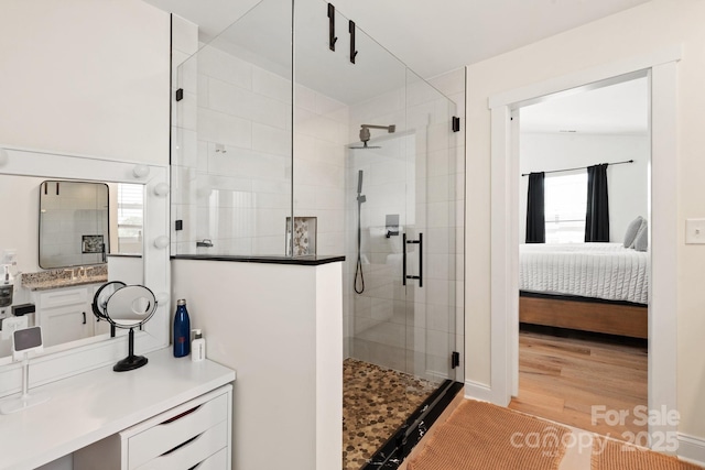 ensuite bathroom with a stall shower, ensuite bath, wood finished floors, and vanity