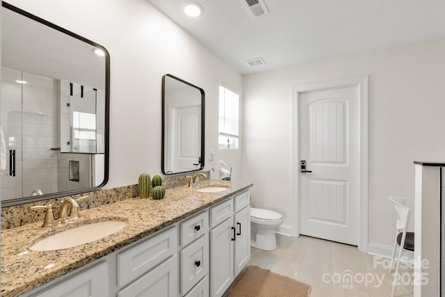 bathroom featuring visible vents, a shower stall, toilet, and a sink