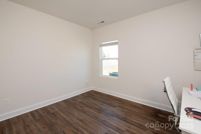 unfurnished office with dark wood-style flooring, visible vents, and baseboards